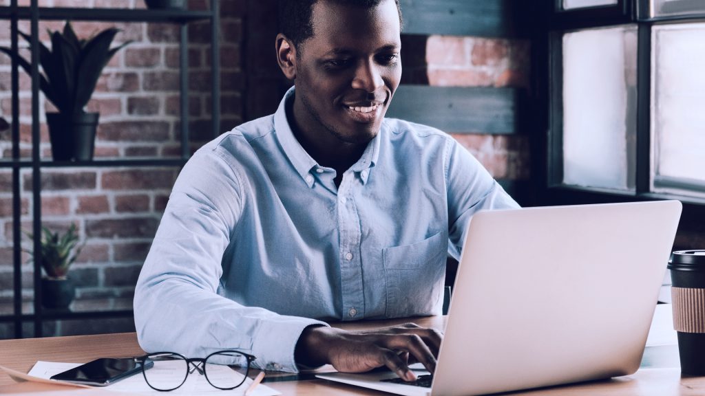 Foto de homem trabalhando junto a um notebook, em casa.