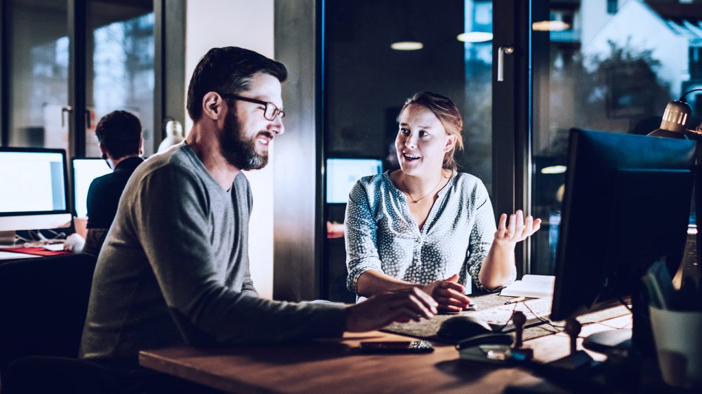 Foto de duas pessoas conversando no trabalho, representando as soft skills e hard skills.